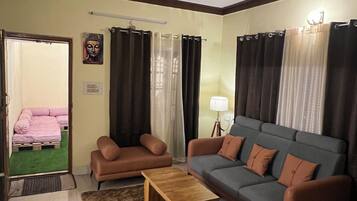 Un salon comprenant un canapé, deux fauteuils, une table basse, un ventilateur de plafond et une lampe.