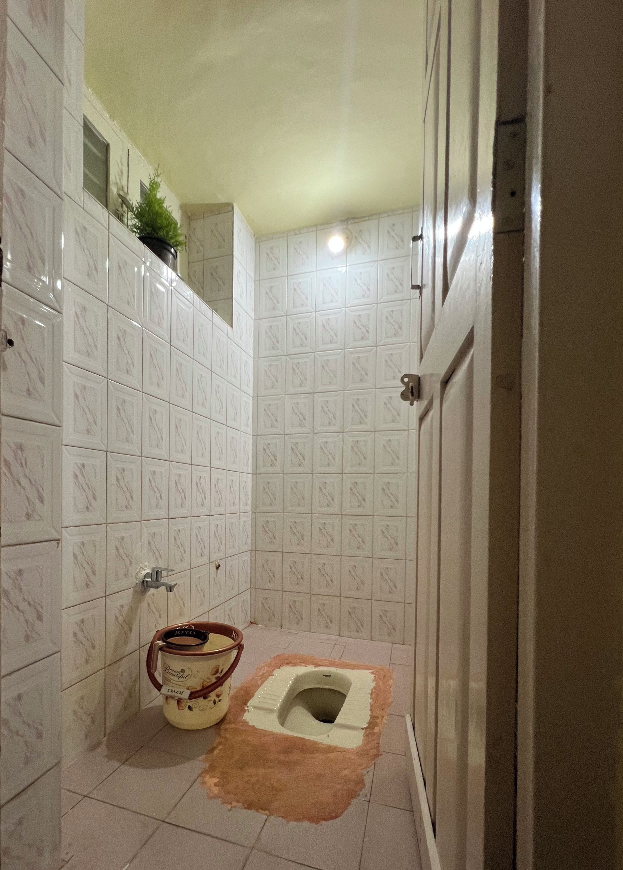 Een badkamer met witte betegelde wanden, een toilet en een douchegedeelte.