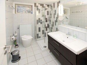 Ein modernes Badezimmer mit Dusche, Toilette, Waschbecken und einem großen Spiegel.