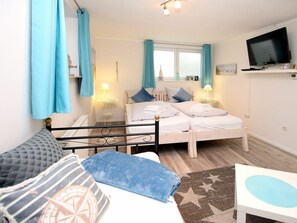 Ein Schlafzimmer mit zwei Betten, einem Fernseher und einem Fenster mit Vorhängen.