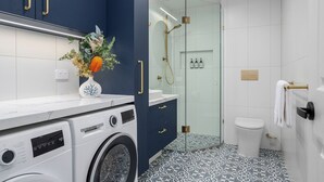Un baño moderno con lavadora, cabina de ducha de vidrio y baldosas de suelo estampadas.