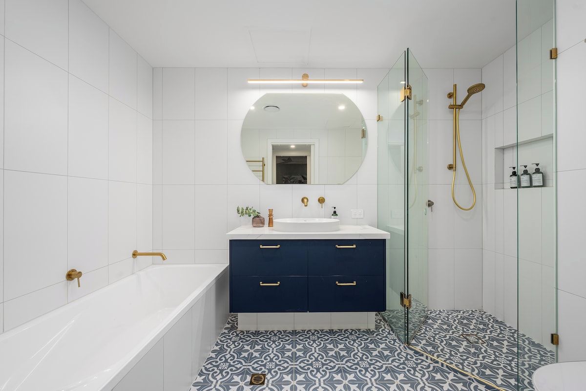 A modern bathroom with a bathtub, a sink with a mirror above, and a shower area.