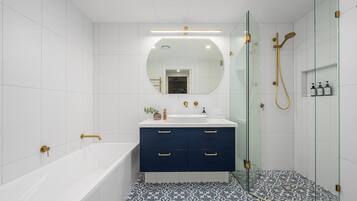 A modern bathroom with a bathtub, a sink with a mirror above, and a shower area.