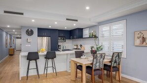 Una cocina moderna con una isla central, taburetes de bar y una mesa de comedor para cuatro.