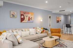 A modern living room with a sofa, armchairs, a coffee table, and artwork on the walls. - Beachfront 3BR Retreat w Parking, Pool and Tennis (Saint Kilda West)