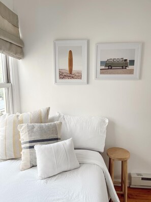 A bedroom with a bed, pillows, a small stool, and two framed pictures on the wall. - Cozy 2-bedroom Beach Bungalow in lovely Ocean Grove, NJ with AC (Neptune Township)