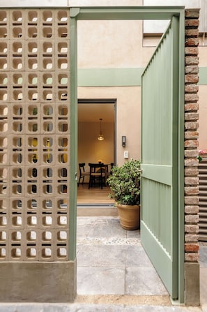 A doorway with a grid-like pattern, leading to an interior space with a dining area and a potted plant. - Zaterra: Ground-Floor Loft with Private Patio in Roma Norte (Ciudad de México)