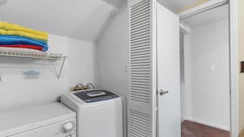 A laundry area with a washing machine, a drying rack with folded clothes, and a closed door.