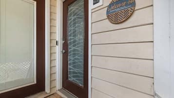 A house entrance with a brown door, a glass door with a metal handle, and a welcome sign on the wall.