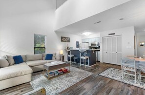 A modern living room with a sofa, coffee table, and a dining area with a table and chairs.