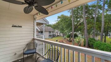 A covered outdoor area with two chairs, a ceiling fan, and a sign reading 'Pool Towels'.