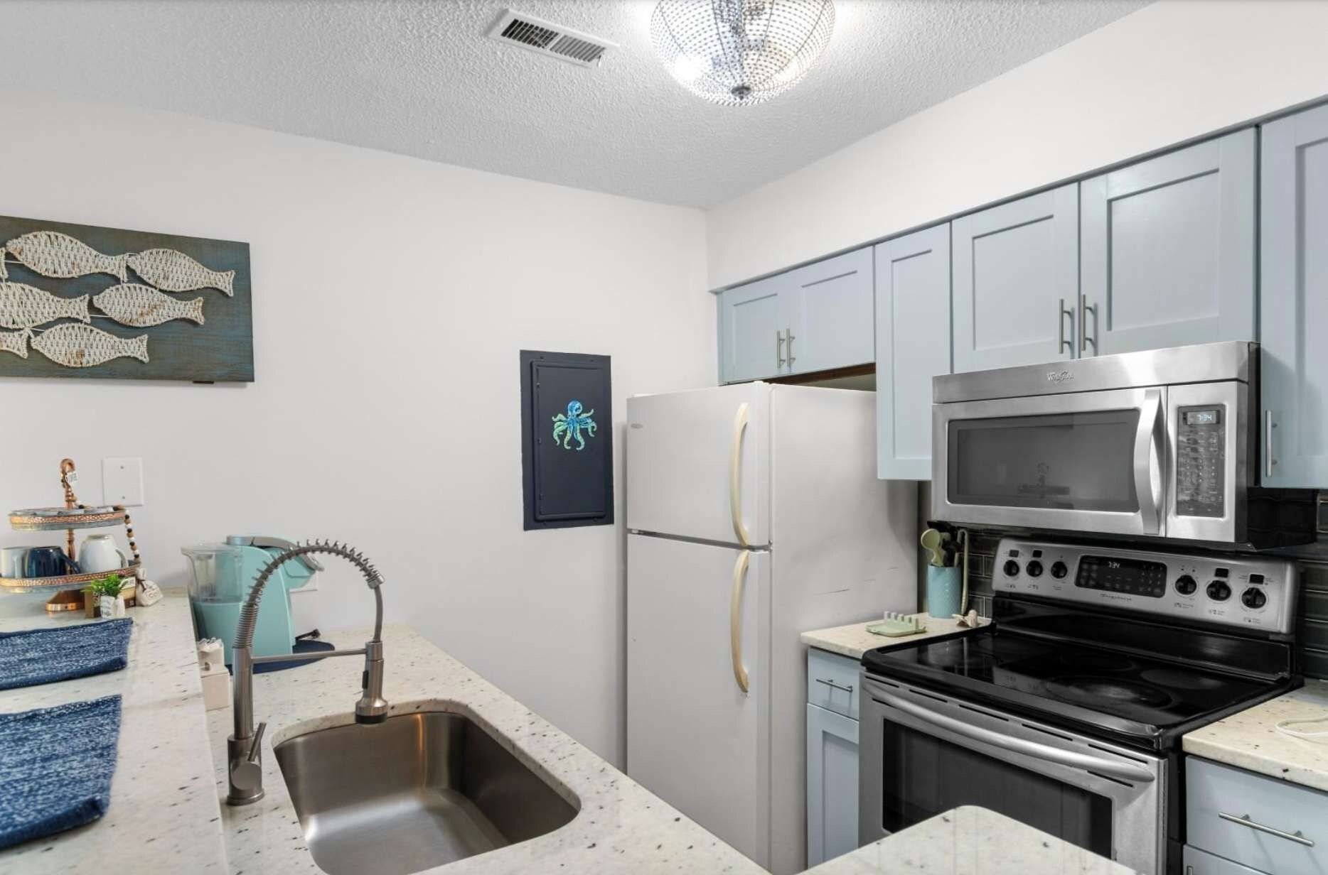 A modern kitchen with stainless steel appliances, a sink, and light blue cabinets.