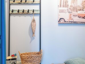 Ein Zimmer mit einer an der Wand befestigten Holzablage, einem gewebten Korb und einem kleinen Spielzeugbus.