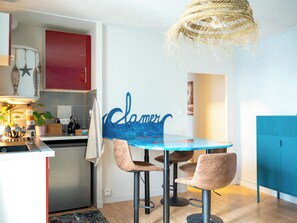 Eine moderne Küche mit Essbereich, ausgestattet mit einem blauen Tisch, zwei Stühlen und einer hängenden Leuchte.