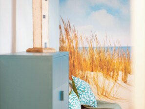 Ein Zimmer mit einem Bett, einem Kopfkissen und einer Wand mit einer Strandansicht.