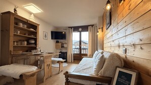 Una stanza accogliente con un letto di legno, un tavolo da pranzo con sedie, una TV e vista sull'esterno.