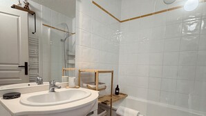 Un bagno con lavandino bianco, specchio e mensole in legno.