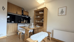 Una cucina compatta con mobili in legno, un tavolo da pranzo per quattro persone e una soffice panca bianca.