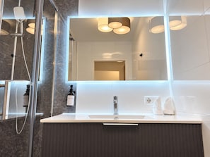 A modern bathroom with a glass-enclosed shower, a large mirror, and a white sink. - Modern 1BR with Private Terrace (Wien)