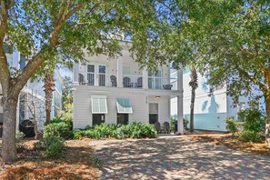 A two-story building with a balcony, a paved driveway, and a view of the water. - 🌴 Vitamin Sea | 4BR Beach Retreat | Pool + Beach Shuttle 🏖️ (Destin)