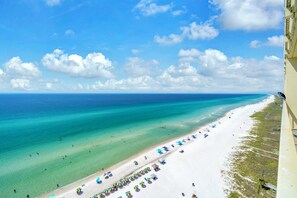 Ein Strand mit klarem türkisblauem Wasser, weißem Sand und einer Reihe von Strandsonnenschirmen.