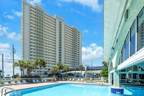 Ein Hotel mit Schwimmbad, Palmen und einem Hochhaus im Hintergrund.