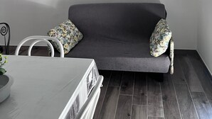 Una sala de estar moderna con un sofá gris, dos cojines estampados, una mesa blanca y una silla blanca.