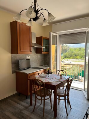 A modern kitchen with wooden cabinets, a built-in oven, and a dining area with a table and chairs. - Apartment 'Casa Del Giglio - MonoVerde' with Balcony and Air Conditioning (Vigliatore)