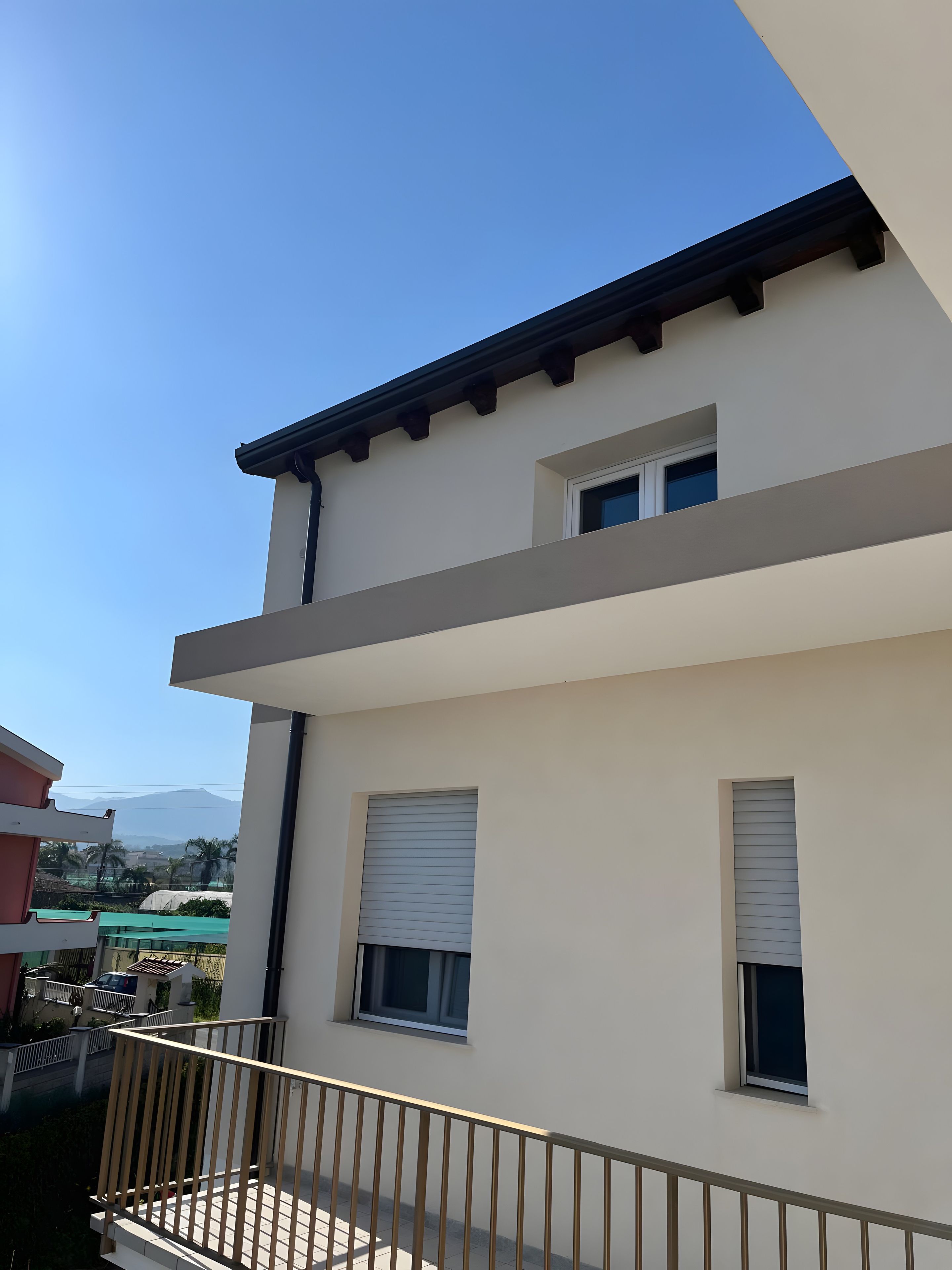 Un edificio moderno de dos pisos con un balcón y vistas del entorno.