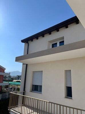 A modern two-story building with a balcony and a view of the surrounding area.