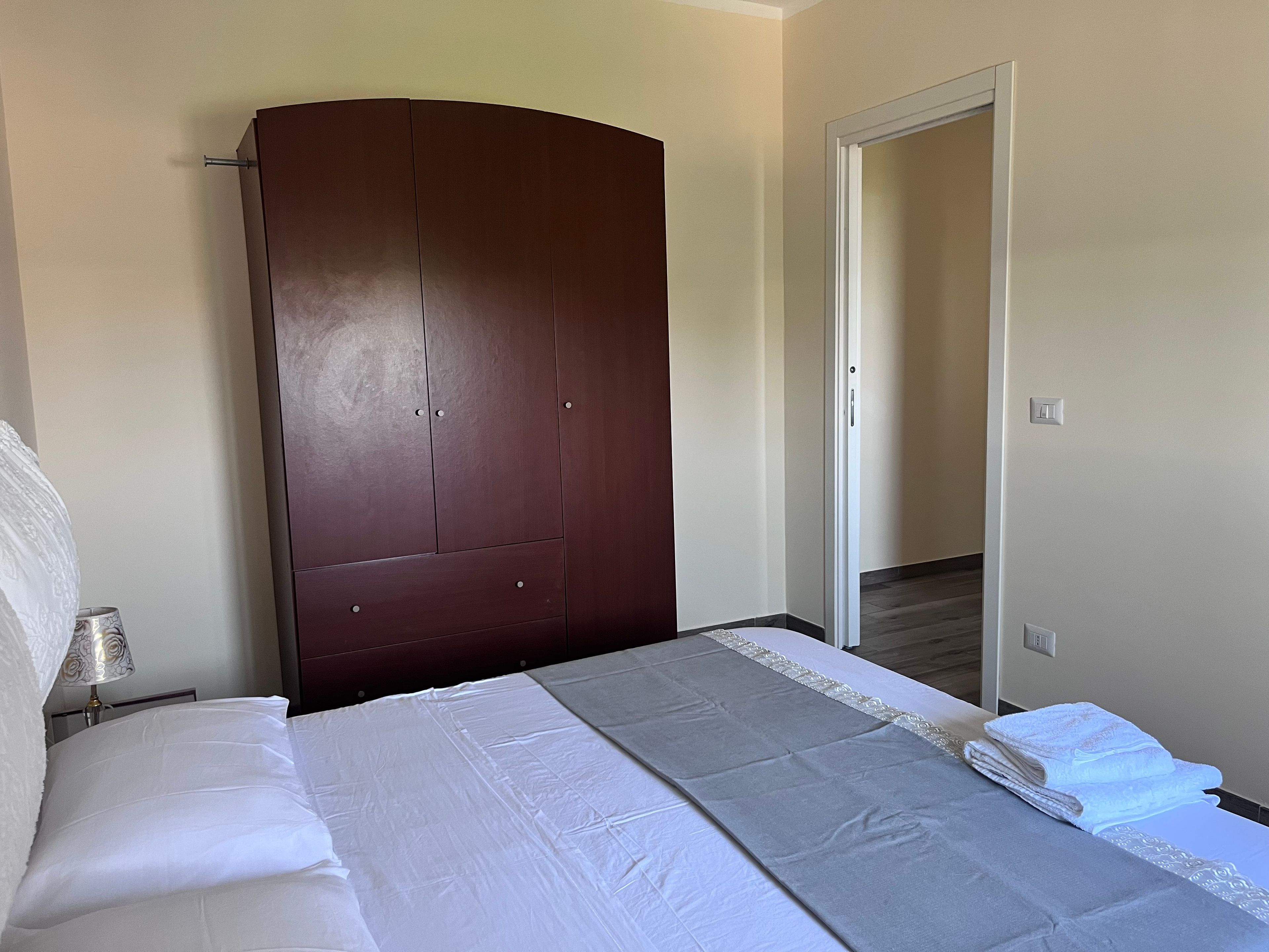 Une chambre à coucher comprenant un lit, une armoire et une porte donnant sur une autre pièce.