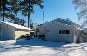 Ein zweigeschossiges Haus mit Garage, überdachter Veranda und einem schnee bedeckten Vorgarten.