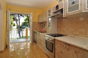 A kitchen with a large window, a stove, and cabinets. - Spacious 100m2 apartment with big terrace & great sea view (Slatine)