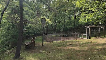 Un parque con un banco de madera, un comedero para pájaros y una zona vallada.