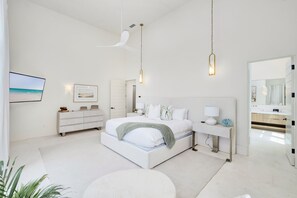 A modern bedroom with a large bed, bedside tables, a desk, a chair, and a large mirror. - Just B | Private Pool | Pickleball Court | Home Gym (Inlet Beach)