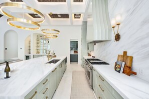 A modern kitchen with marble countertops, a central island, and a built-in oven. - Just B | Private Pool | Pickleball Court | Home Gym (Inlet Beach)