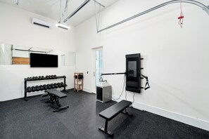 A gym with exercise equipment, a television, and a mirror. - Just B | Private Pool | Pickleball Court | Home Gym (Inlet Beach)
