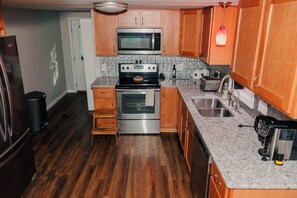 A kitchen with wooden cabinets, a stainless steel oven, a microwave, and a granite countertop.