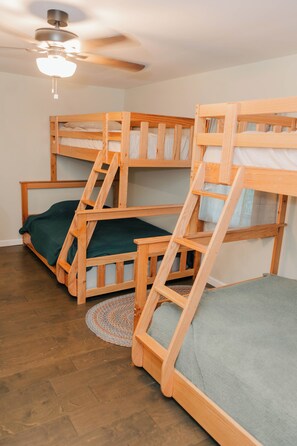 A room with bunk beds, a ceiling fan, and a patterned rug.