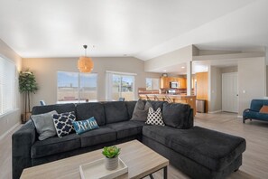 Ein modernes Wohnzimmer mit einem Ecksofa, einem Couchtisch und einer Hängeleuchte.