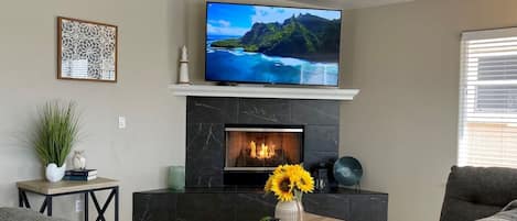 A living room with a fireplace, a television mounted above it, and a sofa.