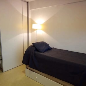 A single bed with a headboard, a bedside lamp, and a wardrobe. - Comfort and relaxation (Puerto Madryn)