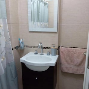 A bathroom with a white sink, a mirror, and a pink towel. - Comfort and relaxation (Puerto Madryn)