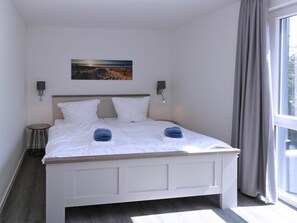 Una habitación de hotel con una cama, un cuadro en la pared y vistas a través de la ventana.