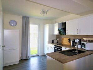 A modern kitchen with white cabinetry, a wooden countertop, and a built-in oven. - House No. 34, Holiday Home Fischerhus (Wangerland)
