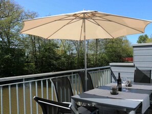 An outdoor dining area with a table and chairs, a large umbrella, and a view of a body of water. - House No. 34, Holiday Home Fischerhus (Wangerland)