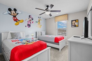 A bedroom with two beds, a ceiling fan, a window with blinds, and wall decals of animated characters. - Resort Escape Near Disney: Poolside Family Fun! (Kissimmee)