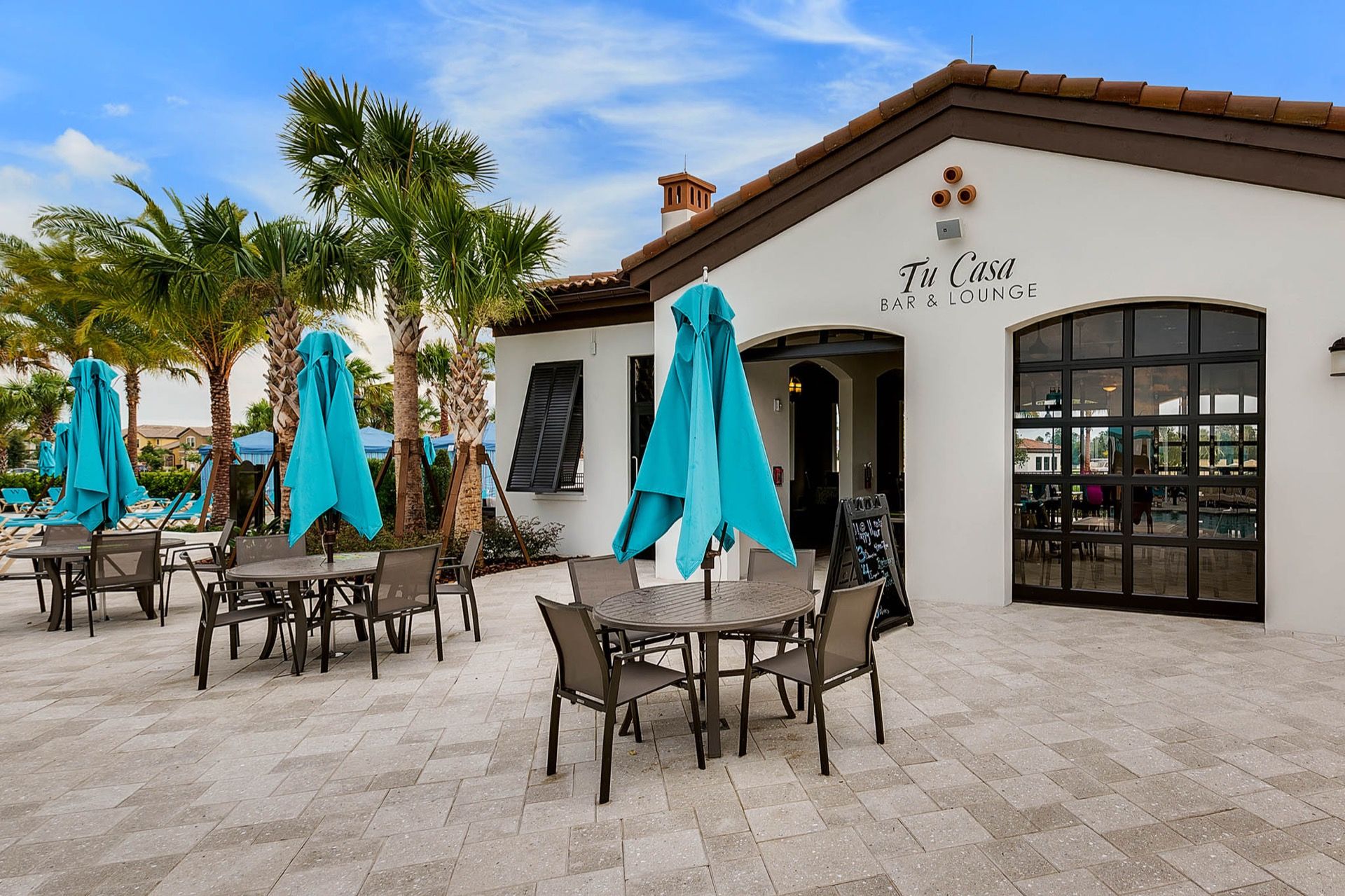 An outdoor seating area with tables and chairs, a pool, and a building labeled 'Tu Casa Bar & Lounge'.
