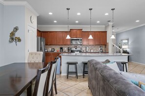 A modern kitchen with wooden cabinets, a stainless steel refrigerator, a built-in oven, and a granite countertop. - Resort Escape Near Disney: Poolside Family Fun! (Kissimmee)