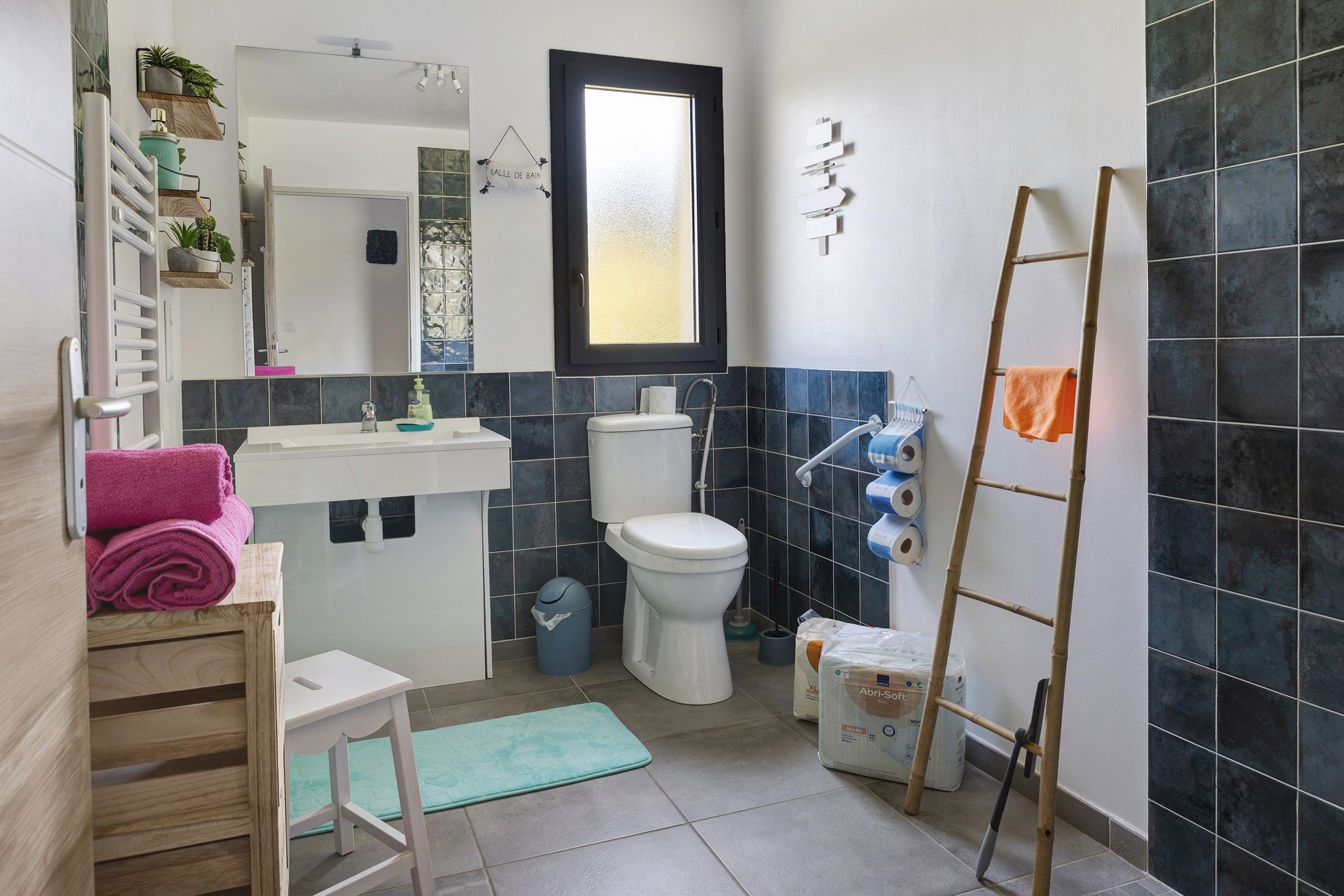Un baño con inodoro, lavamanos, espejo y toallero.